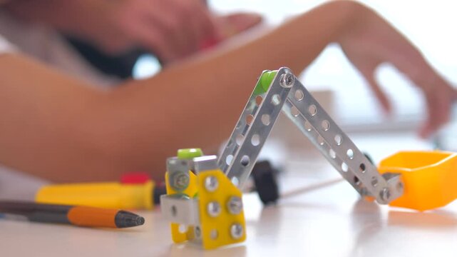 Close up of child hands assembling 3D printed robot model on table. Concept of STEM education, robotics learning, creativity, and technology development
