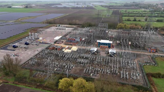 Aerial view of electrical substation, solar panels and battery energy storage systems, contrasting with the green fields, Burwell, United Kingdom.