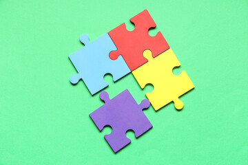 Fototapeta premium Colorful puzzle pieces on green background. Autistic disorder concept