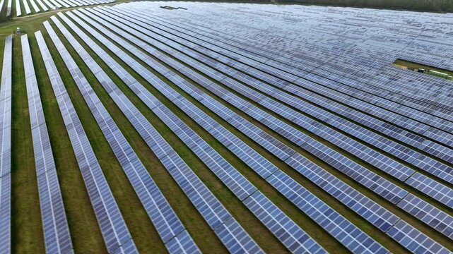Aerial view of rows of solar panels creating a geometric pattern across the landscape, contrasting with the green grass, Huntingdon, United Kingdom.