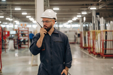 Receiving orders by walkie talkie. Warehouse worker in an industrial environment of a factory or...