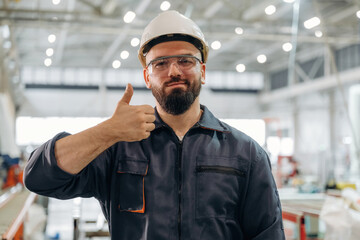 Everything is under control, showing hand gesture. Warehouse worker in an industrial environment of a factory or storage area