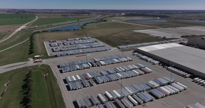 Aerial view of numerous trailers parked in neat rows next to a large building, contrasting with green fields, Greensburg, Indiana, United States.