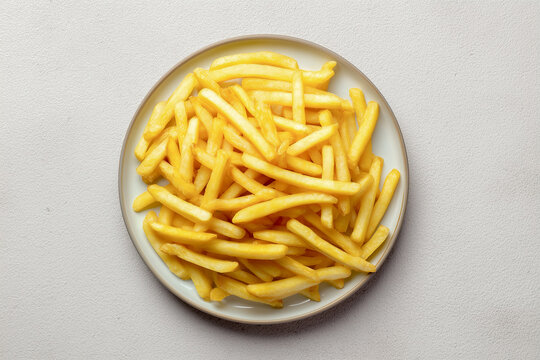 Top view of golden french fries served on a ceramic plate