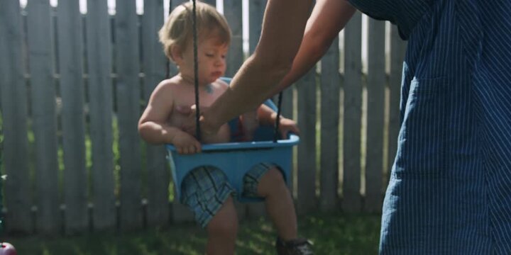 Mother helping her toddler out of a swing