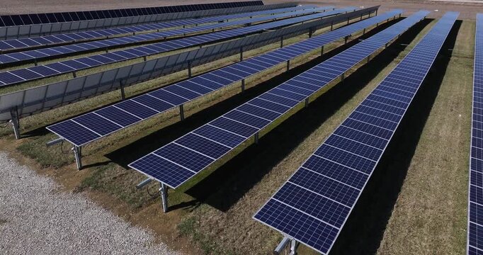 Aerial view of rows of solar panels creating a geometric pattern with contrasting dark blue panels against the light brown ground, Batesville, Indiana, United States.