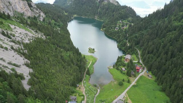 Aerial view of the pristine Lac de Taney nestled amidst verdant hills and rocky slopes, creating a serene tableau of natural beauty, Lac de Taney, Valais, Switzerland.