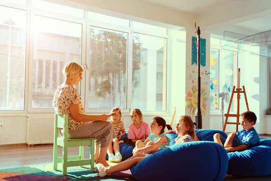 Teacher reading a story to attentive children during cozy classroom story time in a bright kindergarten