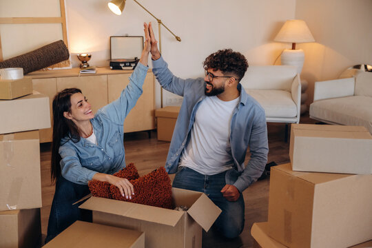 Great teamwork, high five. Playful couple enjoying time together while moving into a new home