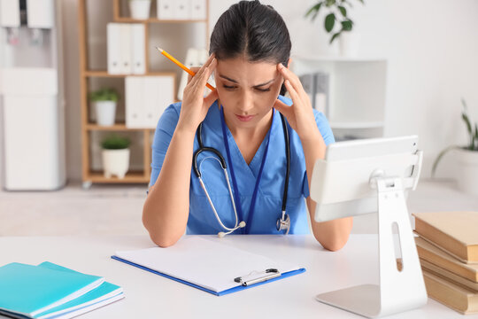 Stressed female medical student sitting at table in clinic