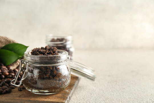 Composition with jar of coffee body scrub and wooden cutting board on light grunge background