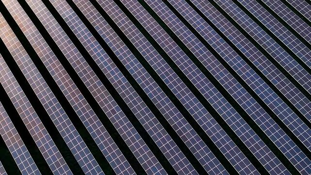 Aerial view of neatly arranged solar panels creating a geometric pattern of dark and light lines in the landscape, Blandford Forum, Dorset, United Kingdom.
