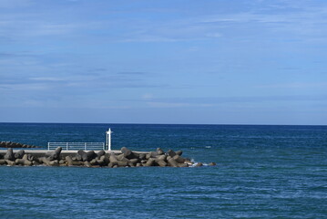 防波堤の先に立つ白い灯台と穏やかな海の風景 White lighthouse at the end of the breakwater overlooking the calm sea © 拓也 山並