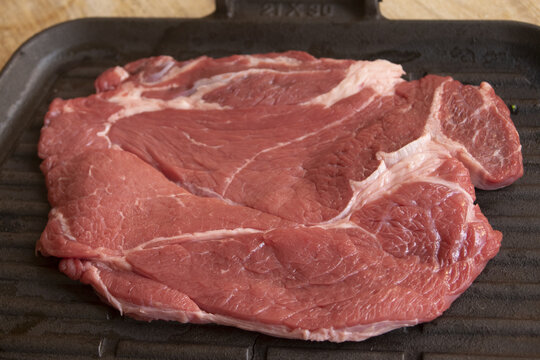 Raw beef chuck steak on cast iron griddle