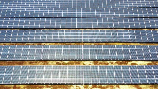 Drone shot of rows of solar panels at modern power farm, highlighting structured grid pattern and sustainable generation of clean renewable electricity