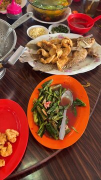 Vertical footage of Chinese Restaurant Table with Deep Fried Fish, Stir Fried Chinese Greens, Fried Rice and Soup on Lazy Susan.