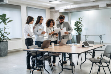 Fototapeta premium Papers, documents, reading, sharing data. Group of people are working in the office together as a team