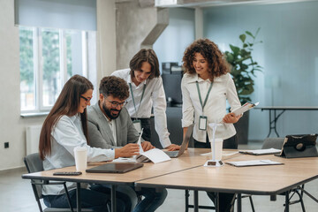 Fototapeta premium Busy day, by the table. Group of people are working in the office together as a team