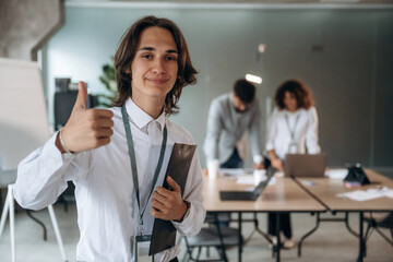 Fototapeta premium Thumb up hand gesture. Group of people are working in the office together as a team