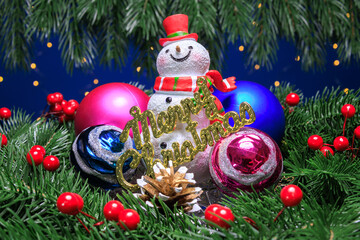 A snowman with letters and colorful balls next to him surrounded by decorated Christmas tree...