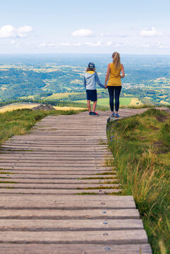 Mother and son walking on nature trail, wooden boardwalk in mountain in France, Auvergne. Travel, adventure, exploration concept