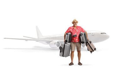 Mature male tourist carrying suitcases and standing in front of an airplane