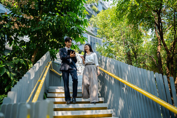 Business colleagues businessman and woman sitting and discussing,planning work using tablet outside...