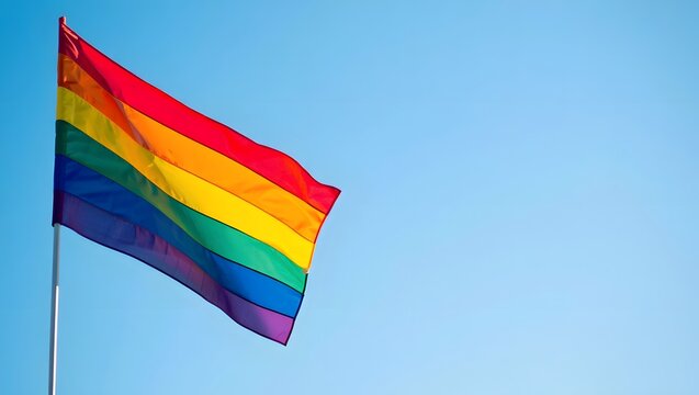 Colorful Rainbow Flag Fluttering Against a Clear Blue Sky