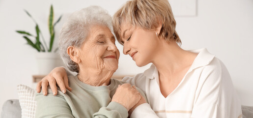Obraz premium Mature woman with her mother hugging on sofa at home