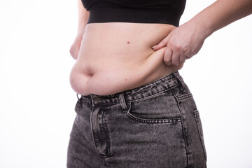 Naklejka premium Fat woman trying to zip up her jeans pants. Women's health. Women body fat belly. Obese woman hand holding excessive belly fat. Diet lifestyle concept, healthy stomach muscle.