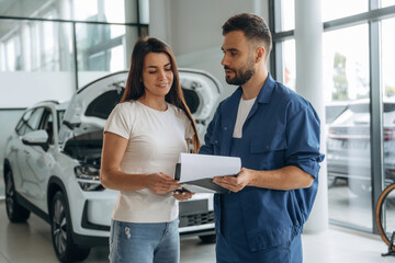 Obraz premium Woman customer is in the car repair service station with mechanic