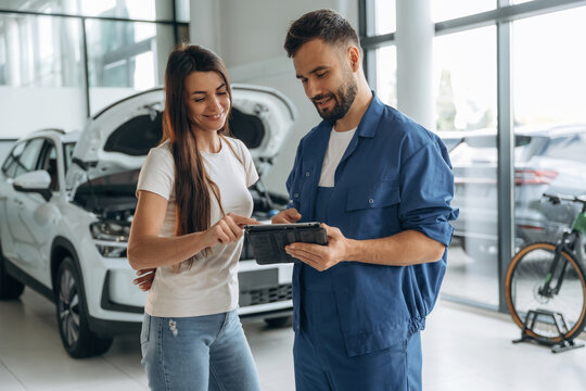Giving the consultation. Woman customer is in the car repair service station with mechanic