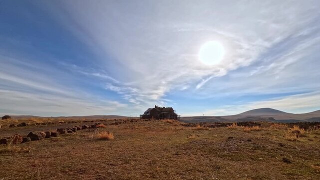 Wide view of Ani Cathedral ruins in Kars, Turkey. Historic Armenian medieval structure set in vast steppe landscape under bright sun and dramatic sky, highlighting architecture and heritage.