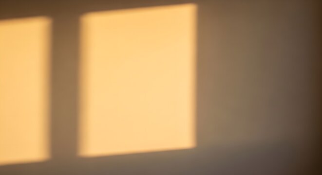 Warm sunlight rectangles cast shadows on textured wall surface