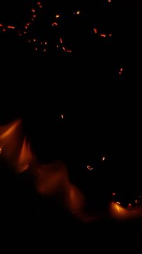 Macro detail of burning steel wool smoldering in the dark, with glowing hot embers and orange sparks flying through the air, creating a fiery and dynamic background texture of combustion