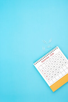 Desk calendar for September 2026 and white paper clip on a light blue background.