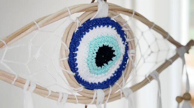 Handcrafted dream catcher shaped like a blue evil eye gently swinging combining spiritual protection amulets from different cultures for good luck. Positive energy