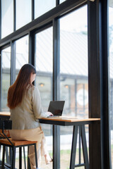 Fototapeta premium Woman working on laptop in modern cafe