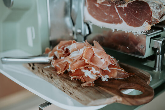 Trancheuse &agrave; jambon en action, d&eacute;coupe de charcuterie sur planche en bois, cuisine et gastronomie 