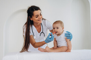 Giving medicine in syringe. Female doctor is taking care of little baby girl in the clinic