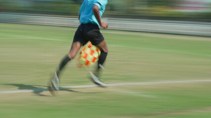 Blurred assistant referee action shot shows legs pumping quickly as he heads to corner field ready to mark play