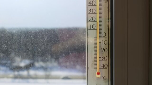 Outdoor thermometer on a dusty window frame displays freezing temperature of minus twenty-five degrees Celsius. Concept of extreme cold weather, heating costs, and harsh winter conditions.