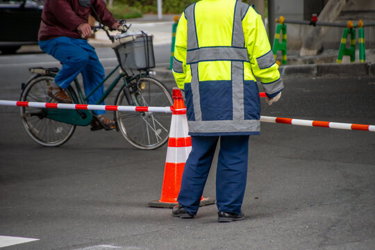 道路工事で通行規制された大通りを見守る交通誘導員