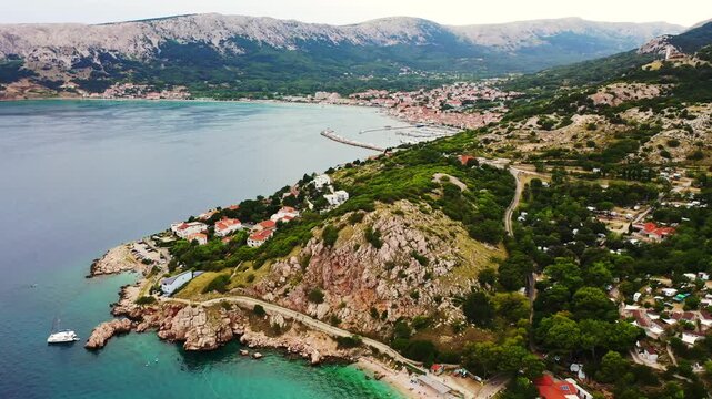 A 4k drone view of the town of Baska in Croatia on the Adriatic Sea, with a view of the mountains and port.