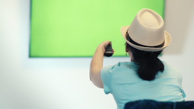 Woman using remote control watching green screen TV, have fun and enjoy