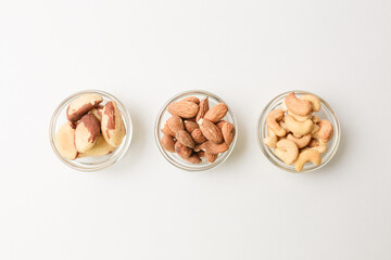Three bowls with Cashew, almond and Brazil nuts on white background. Copy space
