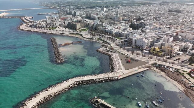 Mediterranean Coastal Harbor with Stone Breakwater, Palm Trees and Historic Waterfront Cityscape.  Mola di Bari Coastal Town in Puglia, Italy