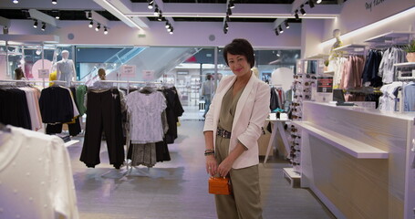 happy woman stands with a handbag in a clothing store and looks at the camera, shopping, have fun and enjoy © vla