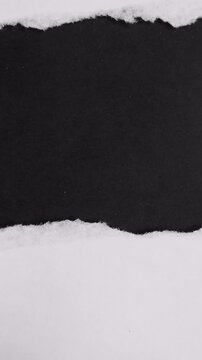 White piece of paper being torn horizontally, from left to right, revealing a solid black background underneath. This dynamic transition creates a central space for copy or imagery
