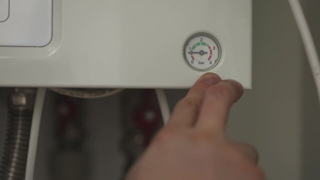 Man pointing to barometer on the panel of the gas boiler and making higher water pressure. 4K